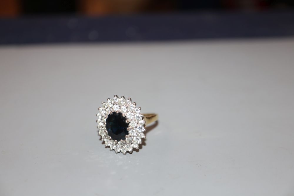 A modern 18ct gold, sapphire and diamond set oval cluster ring, size L, gross 7 grams.